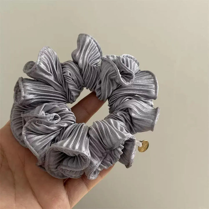 An image of a   Pleated Charm Scrunchie by  Mirra Masa